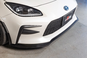 White Toyota GR86 with the GROW Design gloss black front spoiler and garnish, front three-quarter view