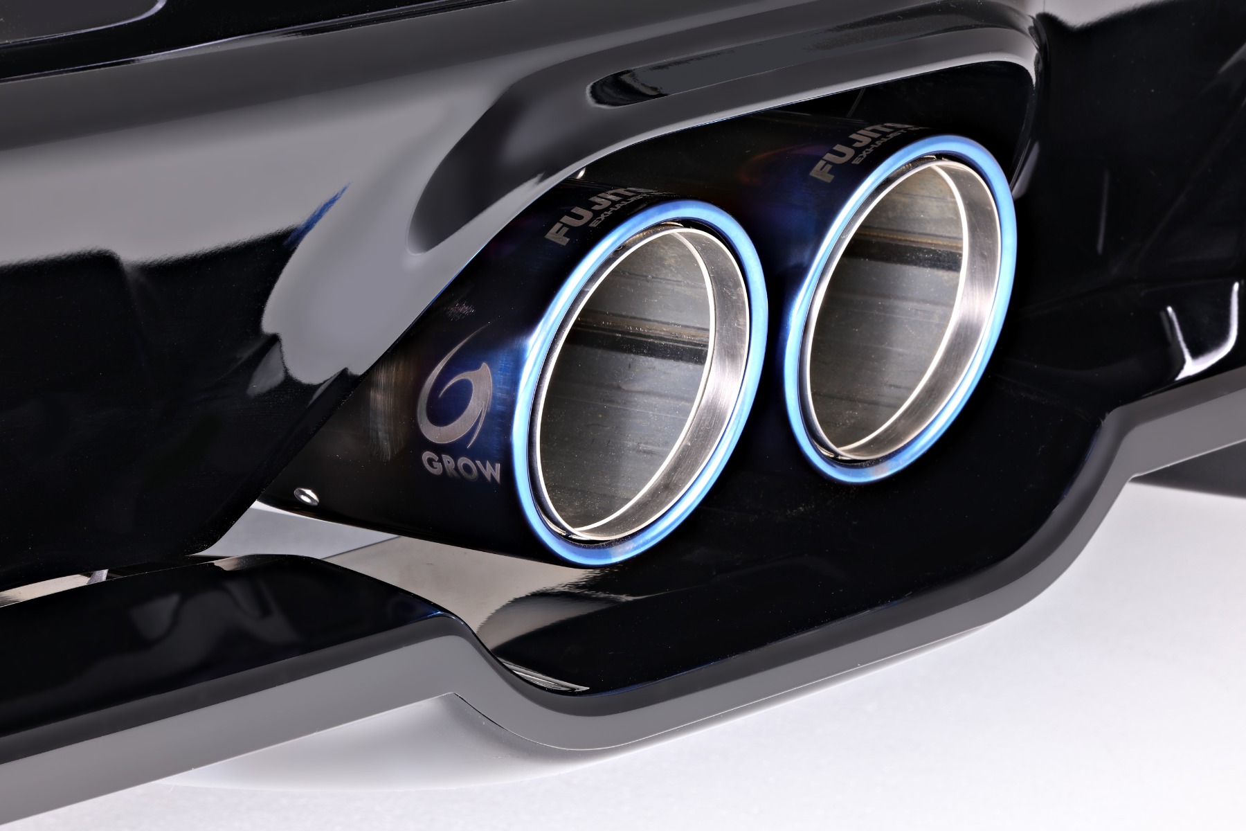Close-up of GROW x FUJITSUBO exhaust tips with blued finish set in the GROW Design rear diffuser on a Toyota GR Corolla