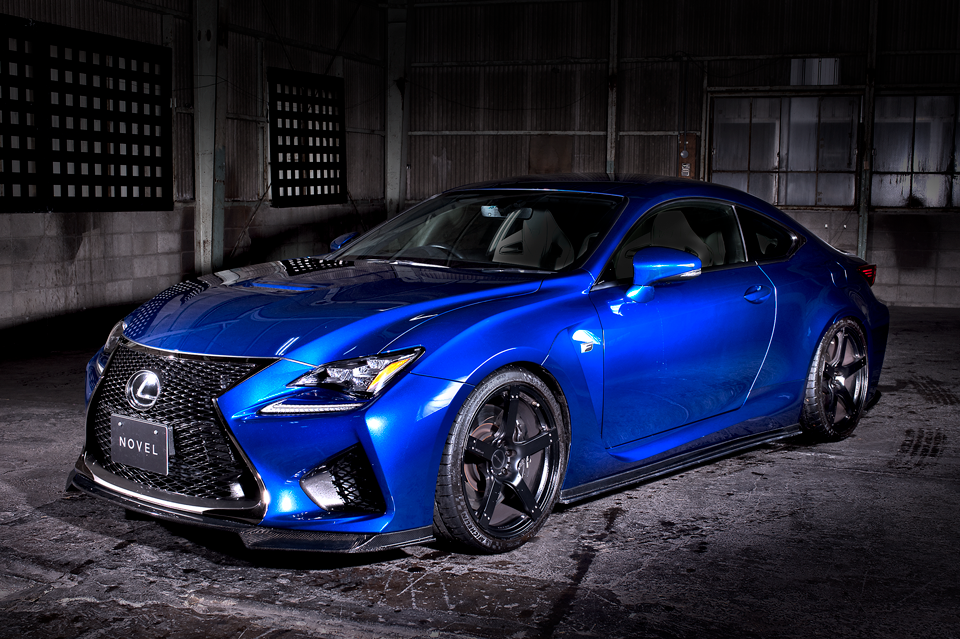 Blue Lexus RC F with the NOVEL Racing Japan carbon fiber aero kit and black wheels, front three-quarter view in a warehouse